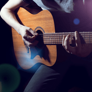 Close-up of hands playing an acoustic guitar with a dark background