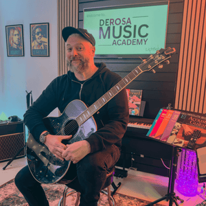 owner of derosa music lichfield holding an acoustic guitar