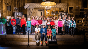 Children's choir on a stage with wooden decor