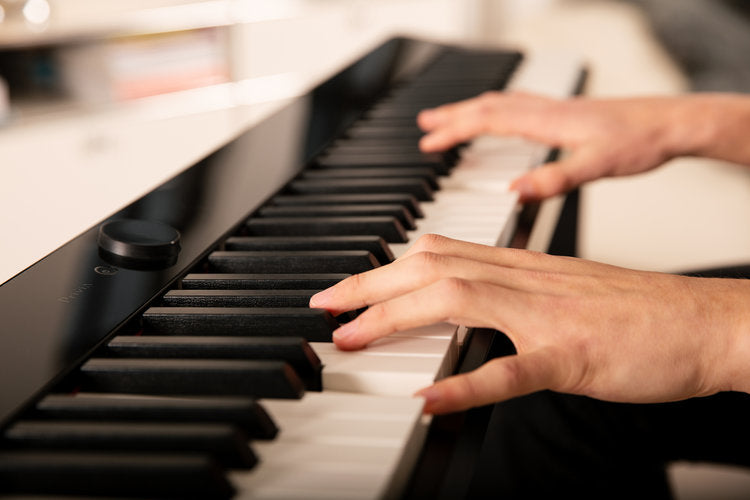 Close-up of hands playing a digital piano