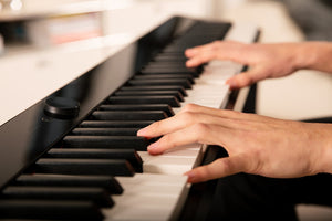 A close-up of hands playing a digital piano