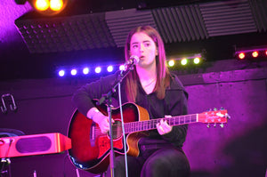 child playing acoustic guitar on stage